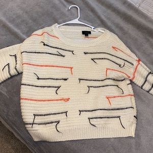 Cream sweater with orange and black details.